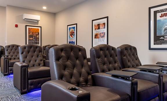 A row of black leather recliner chairs are lined up in a row.