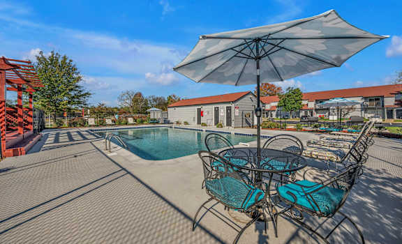 A patio with a table and chairs and an umbrella.