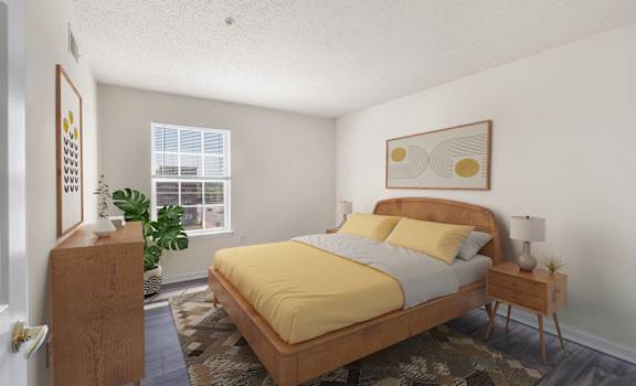 A bedroom with a bed, nightstand, and a plant.