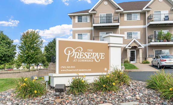 A sign for The Preserve at Commerce in front of a building.