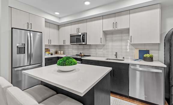 A modern kitchen with a white table and stainless steel appliances.