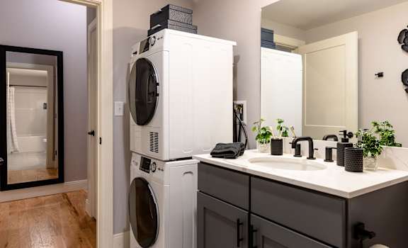 A white washing machine and dryer stacked on top of each other in a laundry room.