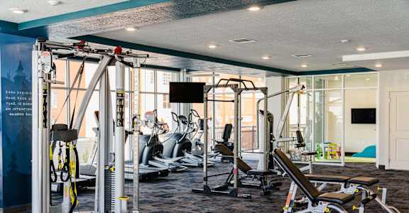 a gym with weights and cardio equipment in a room with glass walls