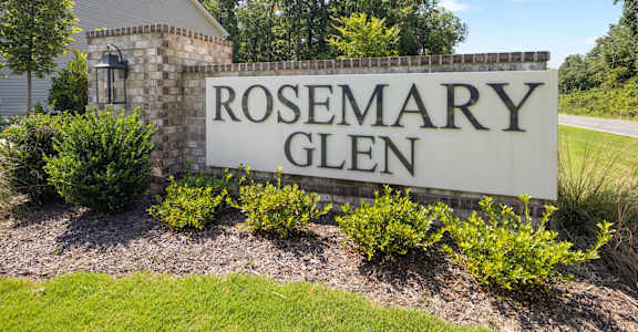 A sign that says "ROSEMARY GLEN" in front of a building.
