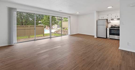 A spacious living room with a kitchen in the background.