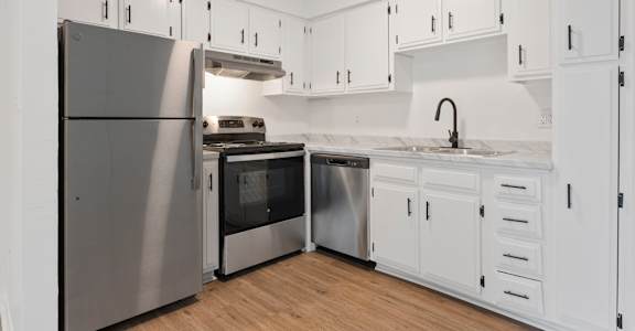 A modern kitchen with white cabinets and stainless steel appliances.