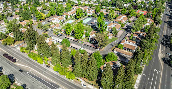 A bird's eye view of a residential area with houses, trees, and roads.