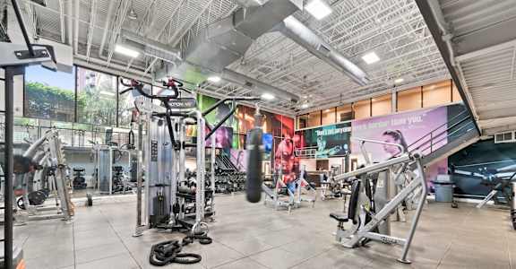 A gym with a variety of equipment including treadmills, weights, and exercise machines.