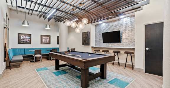 A room with a pool table and a bar area.