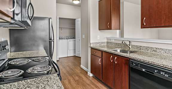A kitchen with a stove top oven and wooden cabinets.