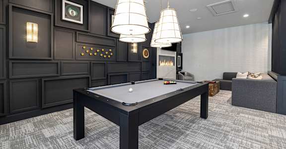 a billiards table in a game room with three lamps