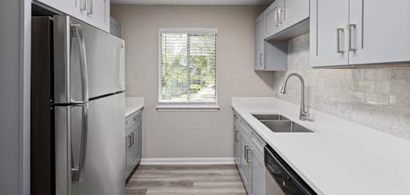 an empty kitchen with white cabinets and stainless steel appliances