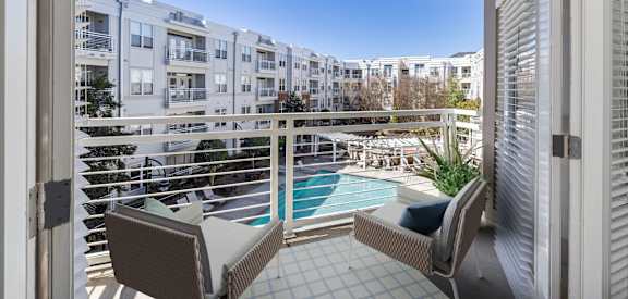 a balcony with two chairs and a view of a pool