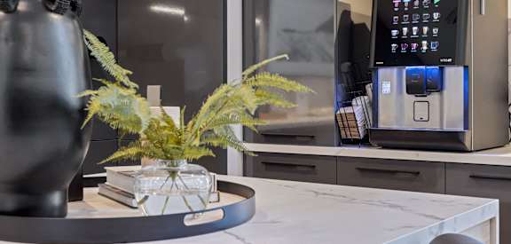 a kitchen counter with a coffee machine and a vase on it