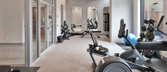A gym with a variety of equipment including treadmills, weights, and exercise balls.