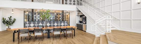 A white interior with a staircase and a long table with chairs.