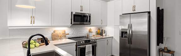 A modern kitchen with a stainless steel refrigerator and white cabinets.