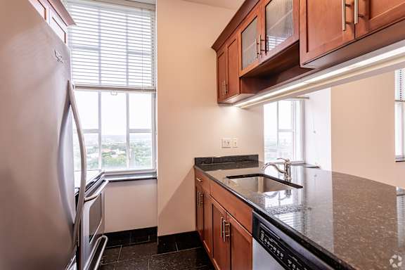 A kitchen with a refrigerator, sink, and cabinets.