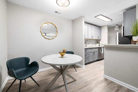 A modern kitchen with a white table and a green chair.