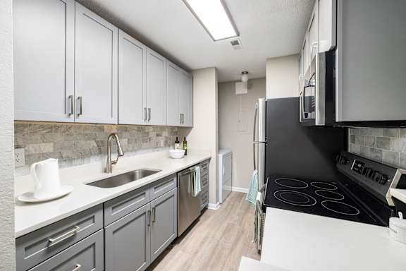 A kitchen with a black stove top oven and a white counter top.