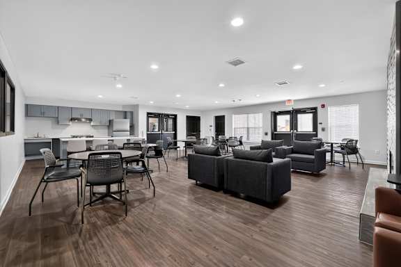 A spacious living room with a kitchen area in the background.