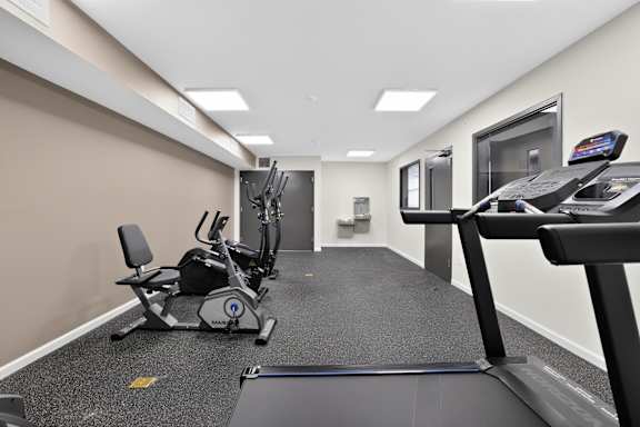 A gym with a treadmill, elliptical trainer, and stationary bike.