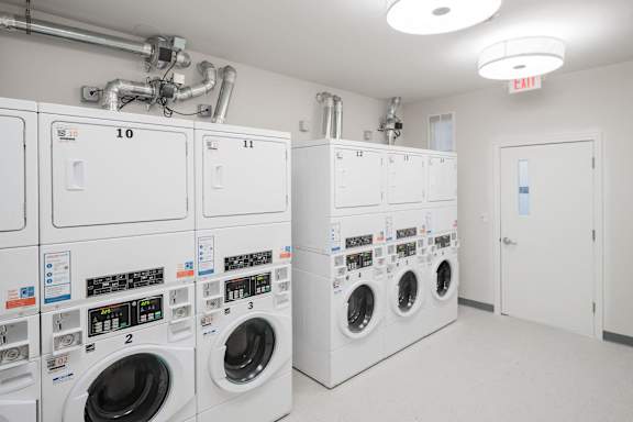 a laundry room with a row of washers and dryers