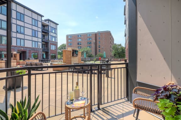 a balcony with two chairs and a bottle of wine on it