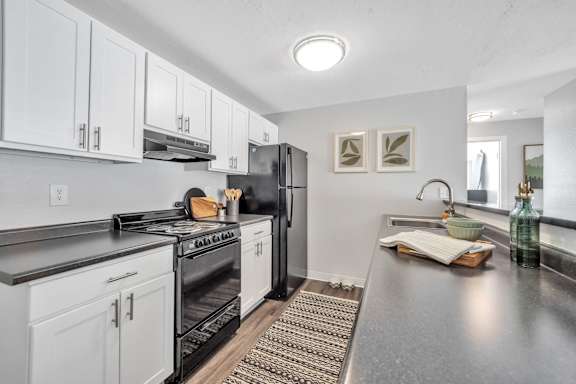 A modern kitchen with white cabinets and stainless steel appliances.
