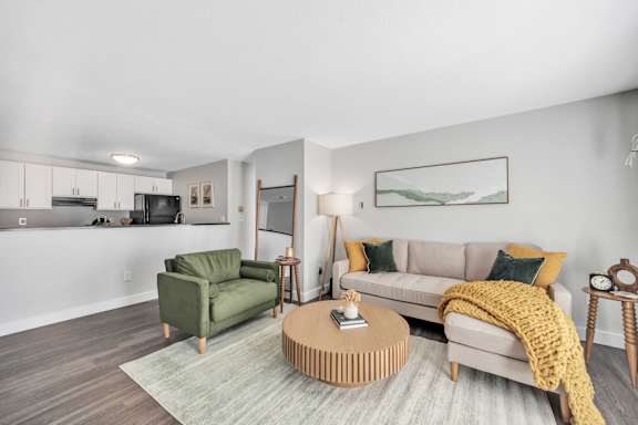 A living room with a green armchair, a beige sofa, and a wooden coffee table.
