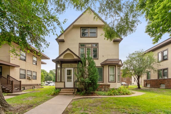 the front of a house with trees and a sidewalk