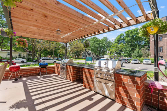 a covered patio with barbecue grills and a wooden roof