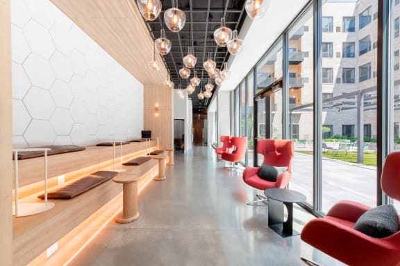 a view down a long corridor with red chairs and wooden tables at TREO Apartments, Cleveland, 44116