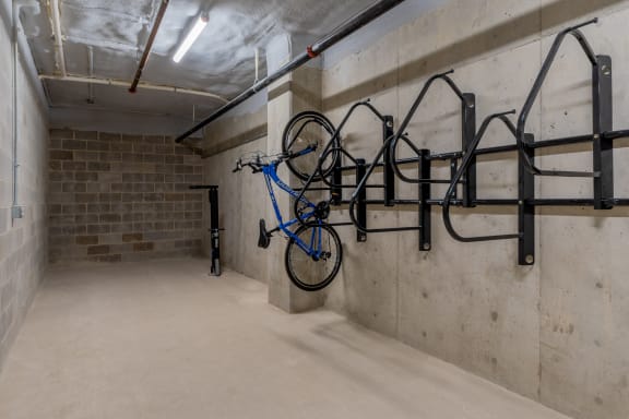 a blue bike is hanging from a bike rack on the wall of a parking garage at TREO Apartments, Cleveland, Ohio