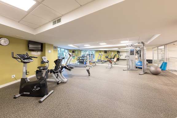 a gym with cardio equipment and weights in a building with yellow walls