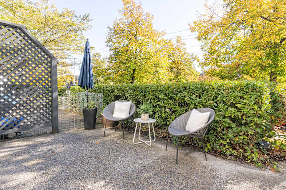 a patio with two chairs and a table next to a hedge