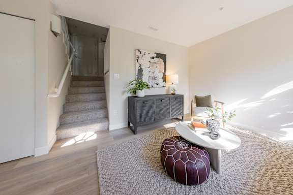 a living room with a couch and a table in front of a staircase