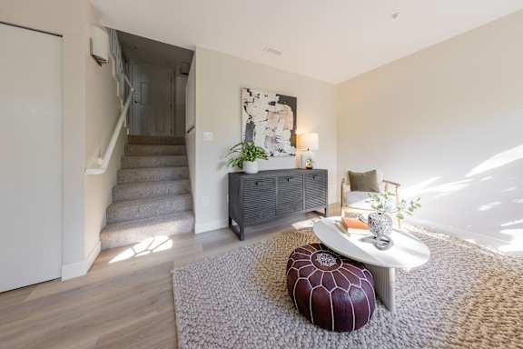 a living room with a couch and a table in front of a staircase