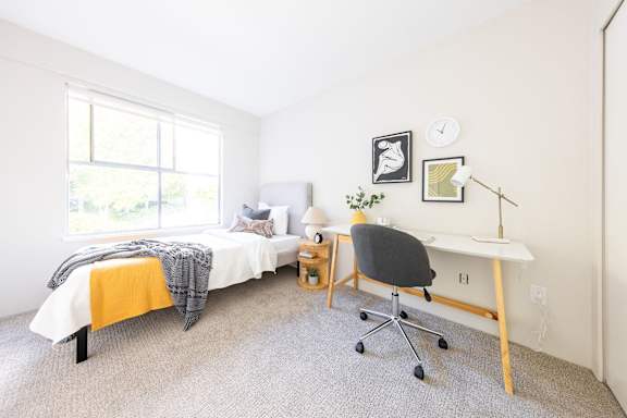 a bedroom with a bed and a desk and a window