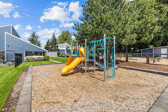 A playground with a yellow slide and a blue structure.