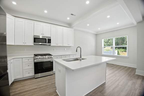 A modern kitchen with white cabinets and stainless steel appliances.