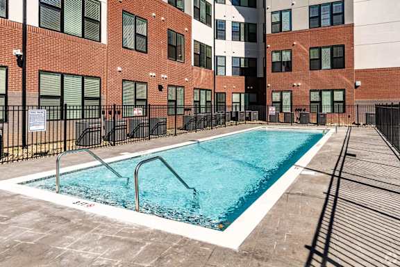 A swimming pool in front of a brick building.