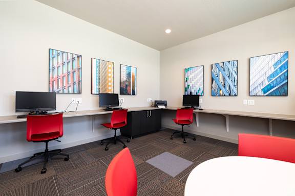 A room with a red chair and a white desk with a computer on it.