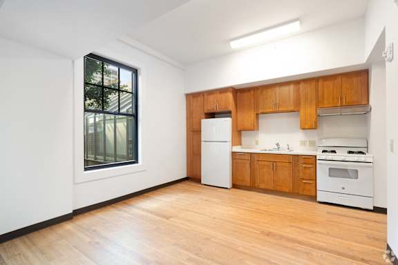 a kitchen with white appliances and wooden cabinets and a window