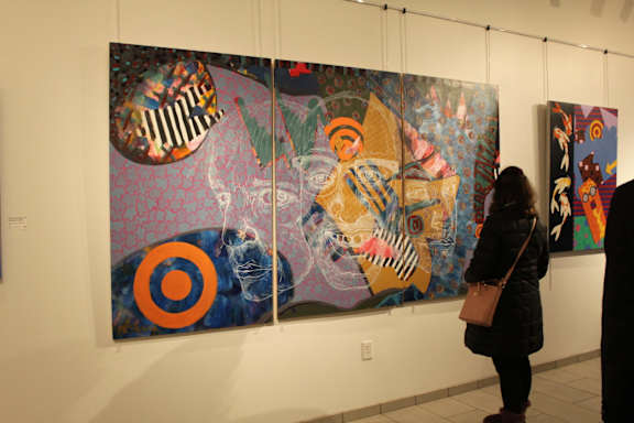 A woman is looking at a colorful painting in an art gallery. at Trio Newton Apartments, Massachusetts