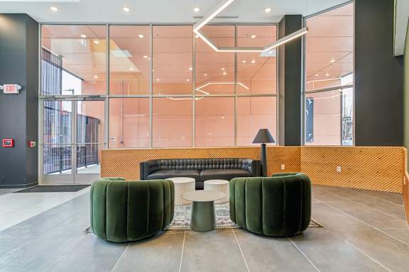 Spacious resident lounge at The Gio Apartments with a modern couch, tables, and chairs.