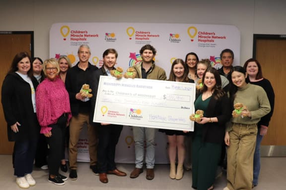 a group of people holding a large cheque for a charity event