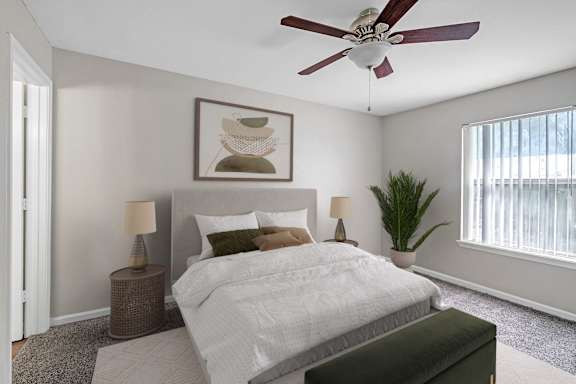 A bedroom with a large bed, a ceiling fan, and a painting on the wall.