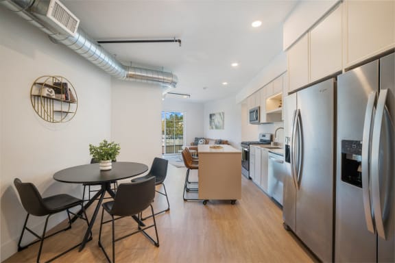 a kitchen and dining area with stainless steel appliances and a table and chairs