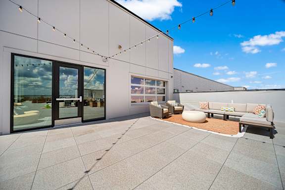 A patio area with a white couch and a string of lights.
